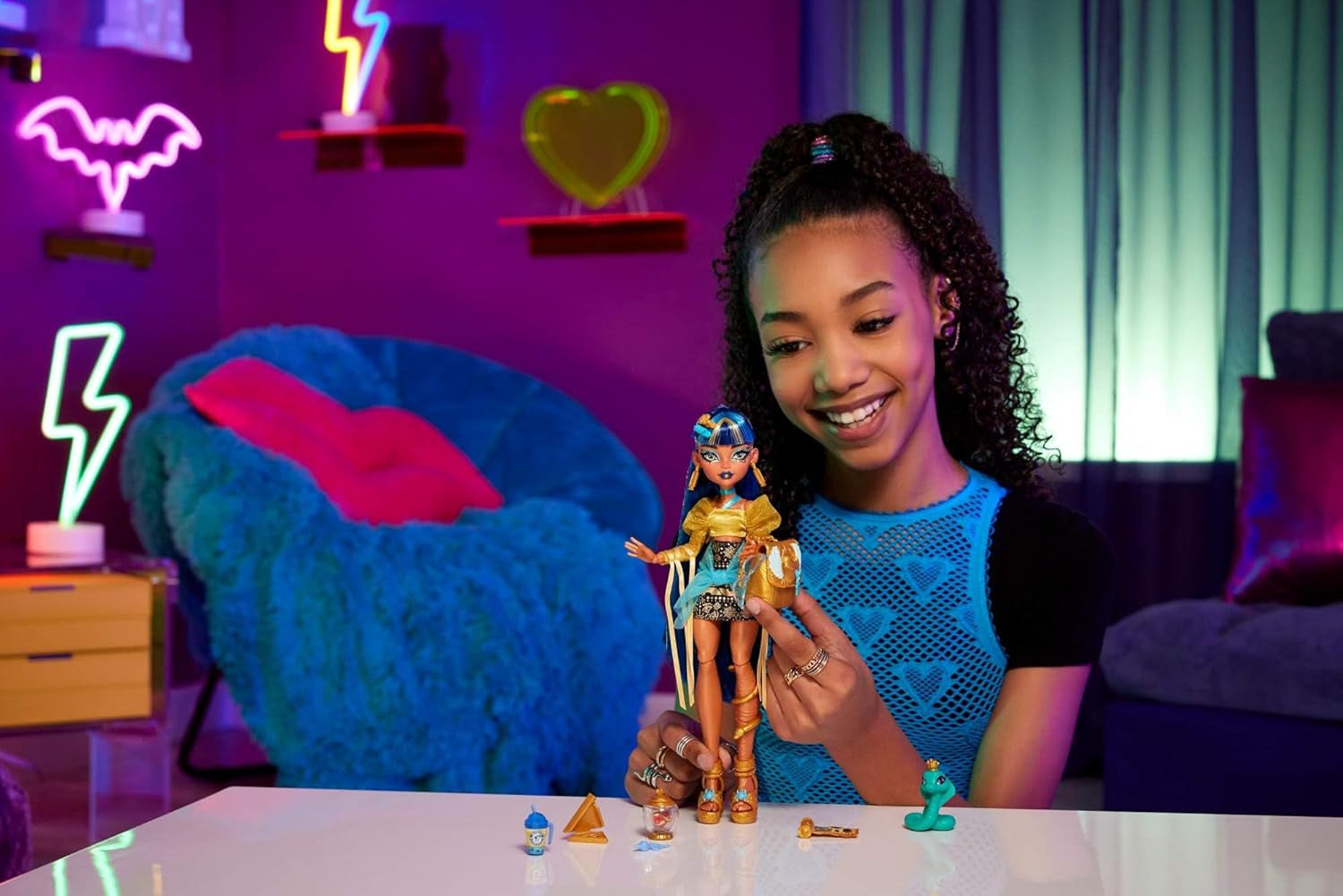 Păpușa Monster High Cleo De Nile într-o bluză aurie și o fustă cu mai multe straturi, include cobra Hissette și accesorii precum un ghiozdan, o gustare și un sul de hârtie igienică, HXH74